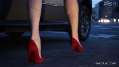 修长的女人的腿在红色高跟鞋在晚上进入停放的汽车苗条的女人的腿在高